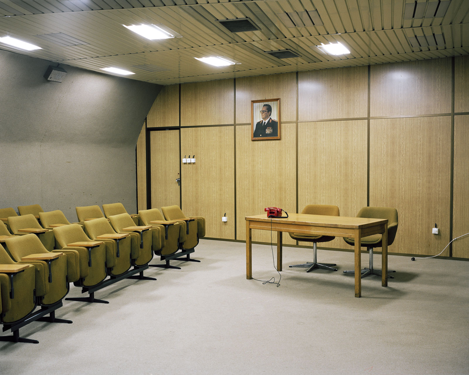 Der Konferenzsaal in Titos Bunker in Konjic, Bosnien. Das Porträt des Präsidenten des ehemaligen Jugoslawiens blickt auf leere Stühle.