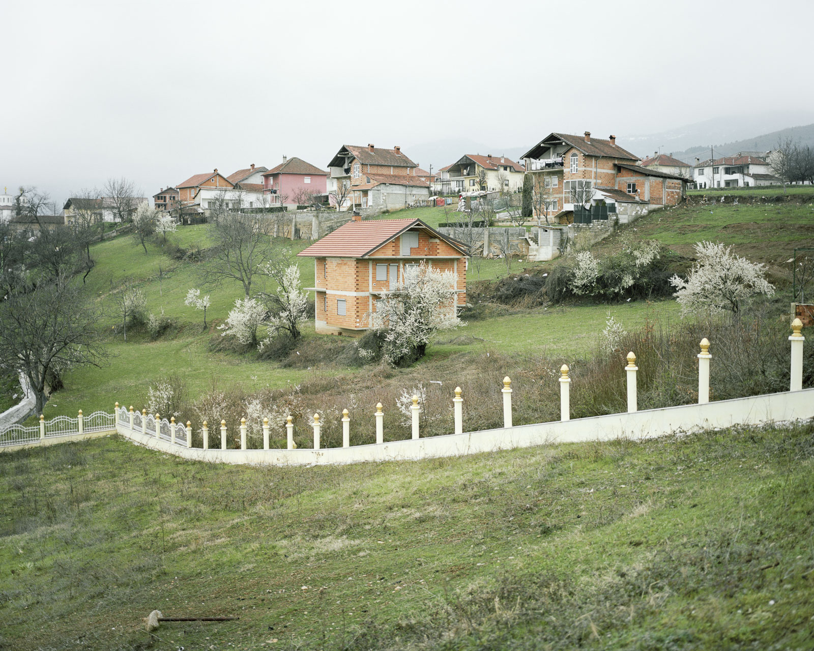 Haus ohne Fassade im Kosovo. Unfertige Bauten sind typisch für diese Region. Der Zaun um das Grundstück ist noch nicht fertig.